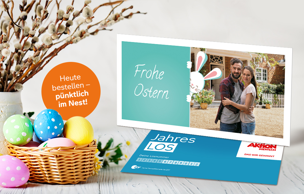 Ein Jahreslos mit persönlichem Foto und Ostergruß steht inmitten einer österlichen Dekoration. In einer Textblase steht: Heute bestellen, pünktlich im Nest!