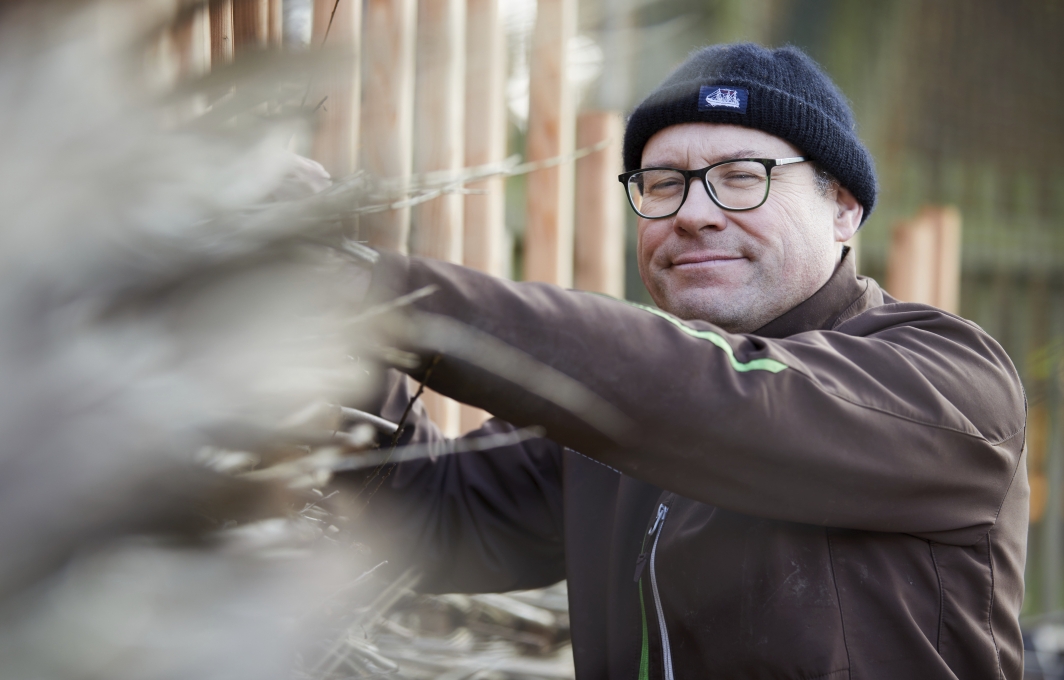 Ein Mann in Arbeitskleidung arbeitet an einem Zaun.