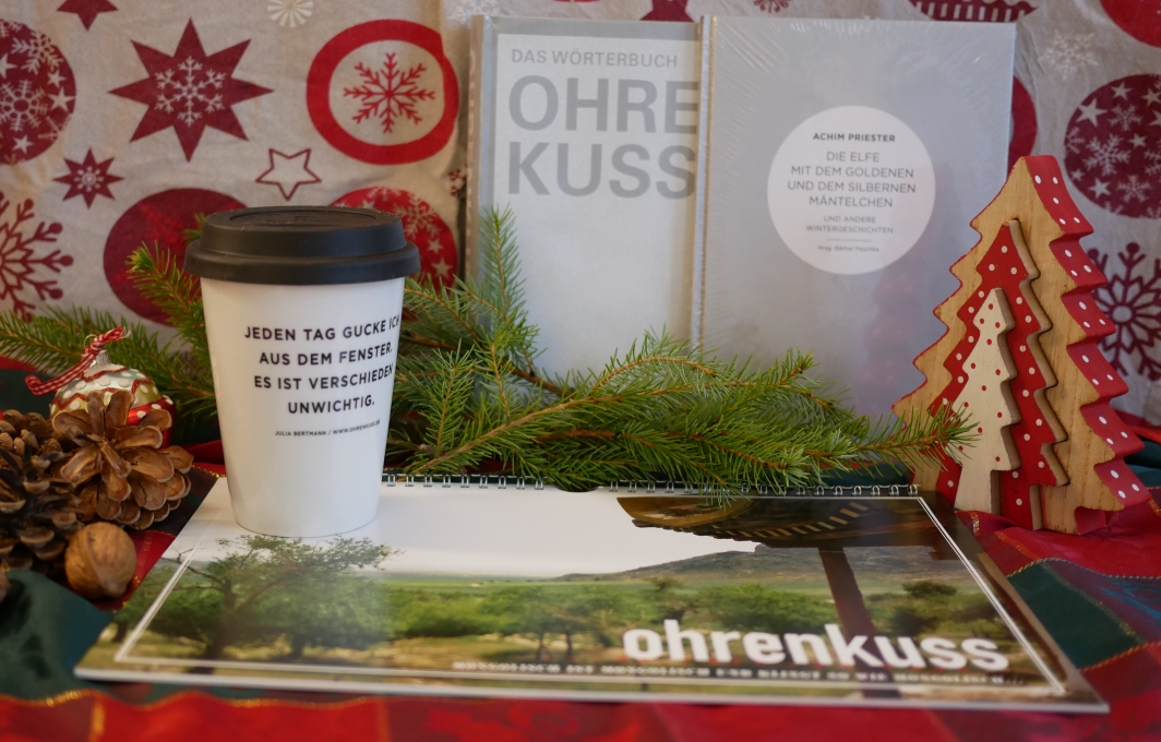 Ein Kaffeebecher, Kalender und Bücher der Ohrenkuss-Redaktion.