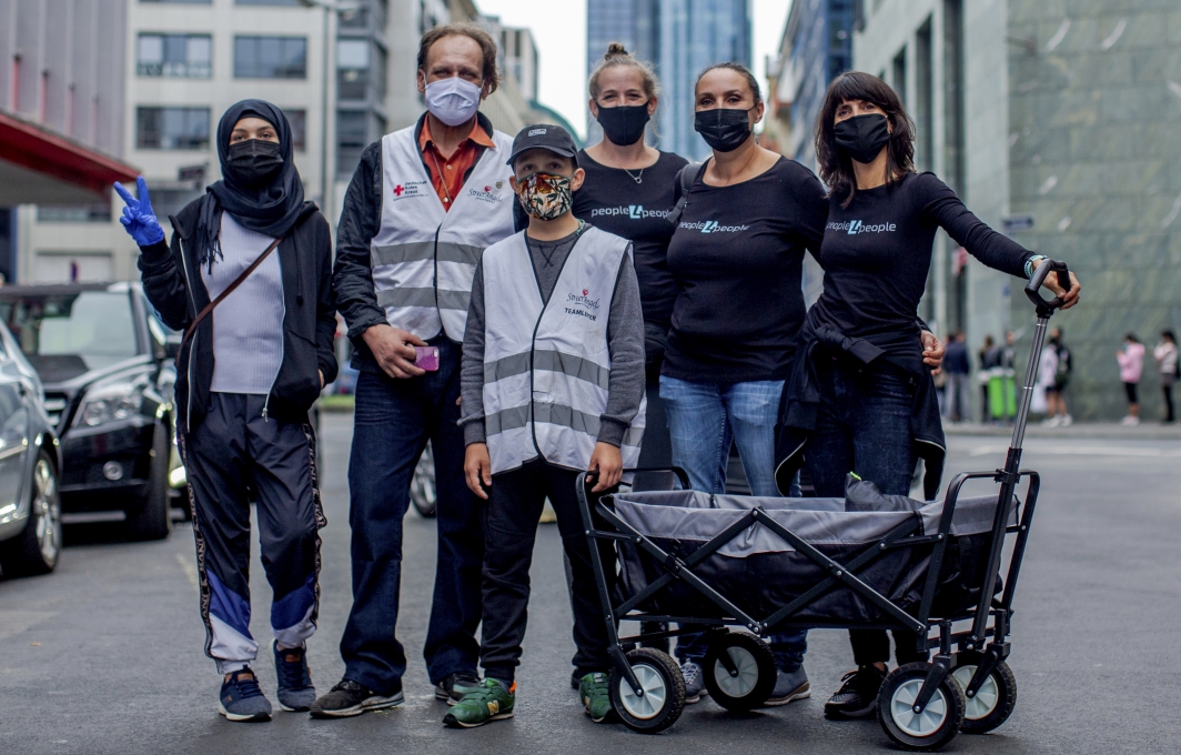 Ein Team aus Ehrenamtlichen. Sie tragen people4people-Shirts und Masken.