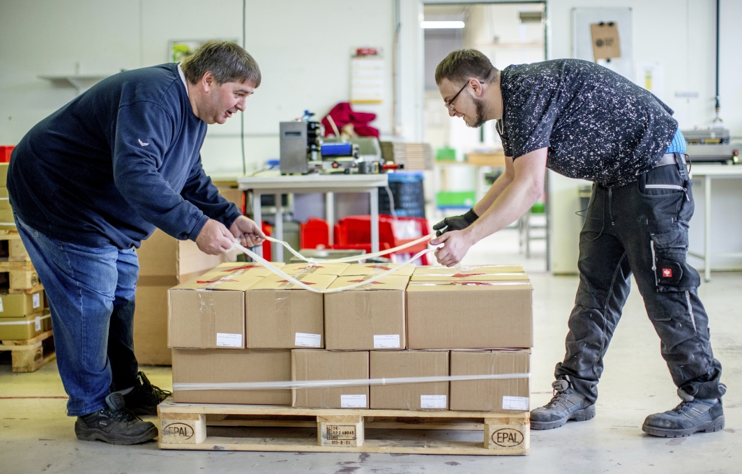 Zwei Männer beladen eine Palette mit Kartons.