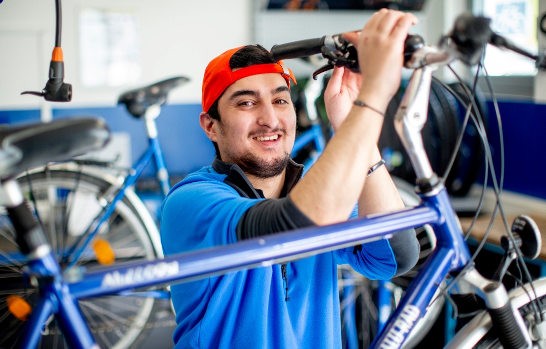 Ein junger Mann mit Kappe repariert ein Fahrrad.