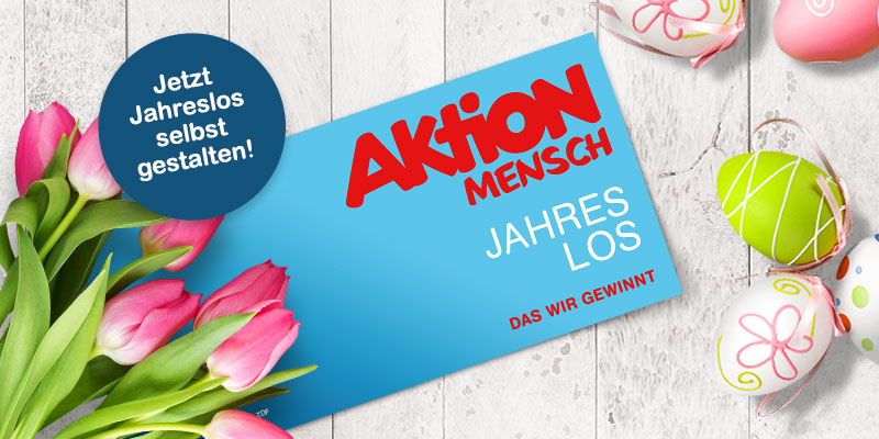 Ein Jahreslos liegt neben Tulpen auf einem Holztisch
