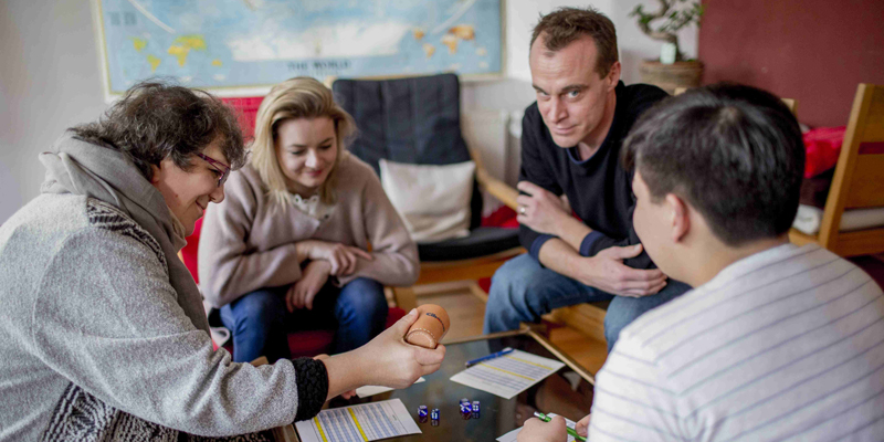 Vier Personen mit und ohne Behinderung spielen gemeinsam ein Brettspiel.