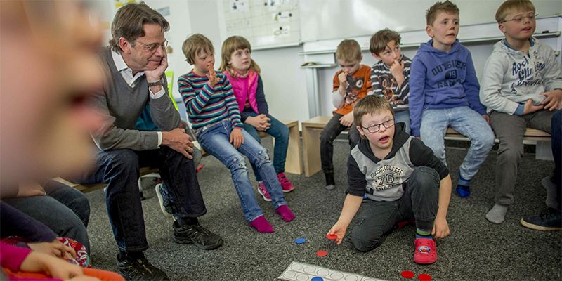 Grundschüler sitzen mit Rudi Cerne im Klassenraum