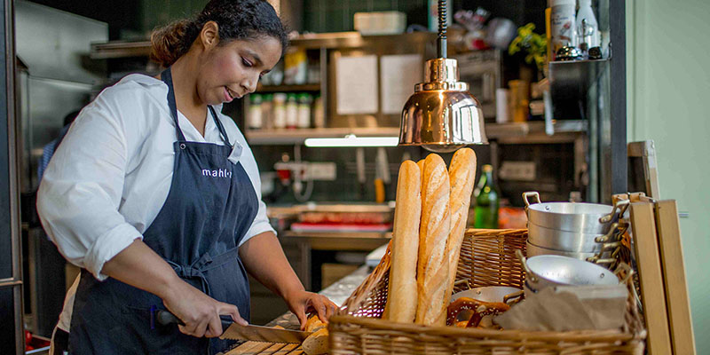 Eine junge Frau schneidet ein Baguette auf