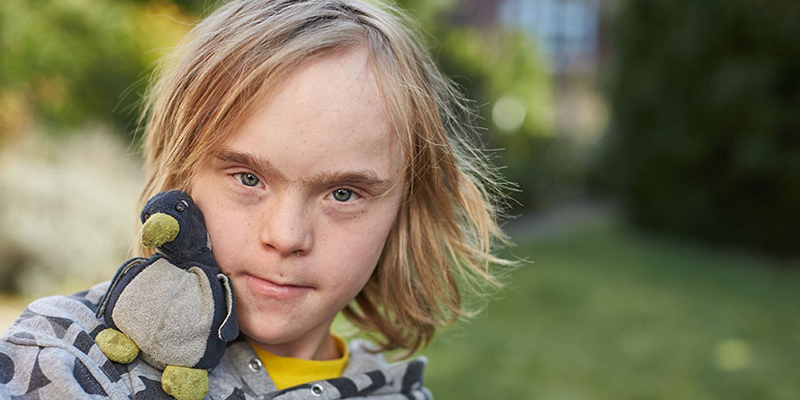 Ein Junge mit Down-Syndrom lacht in die Kamera