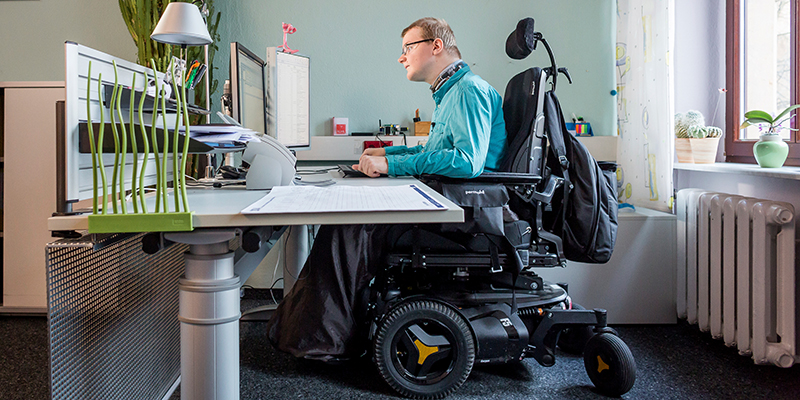 Ein Rollstuhlfahrer arbeitet an einem Computerarbeitsplatz