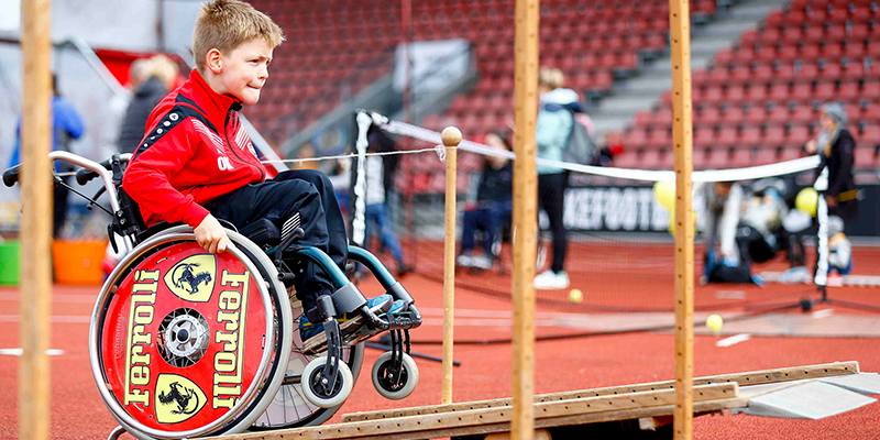 Junge im Rollstuhl fährt über eine bewegliche Rampe