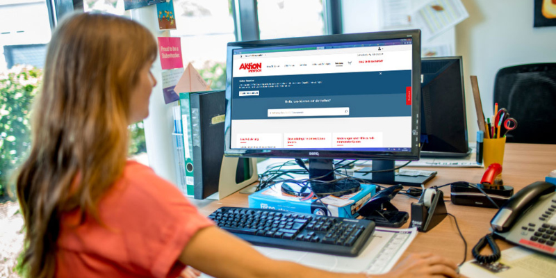Eine Frau arbeitet an einem Computer, auf dem der neue Service-Bereich der Aktion Mensch-Lotterie abgebildet ist.