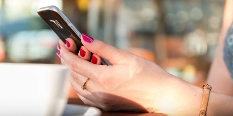 Eine Frau hält ein Handy in der Hand.