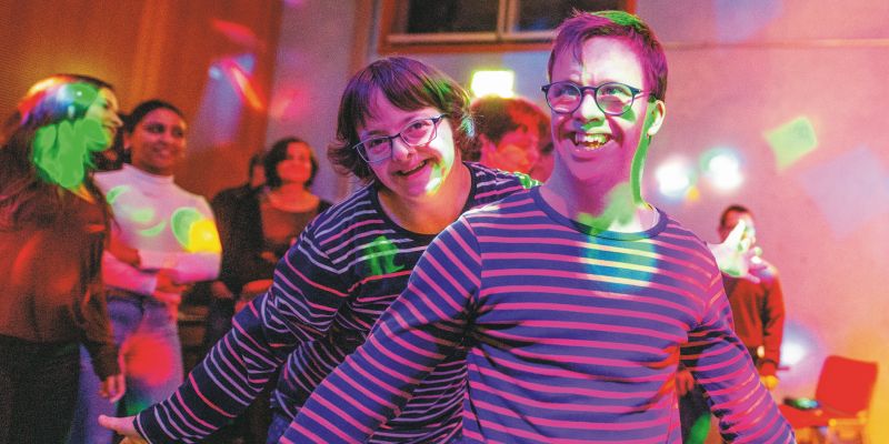 Zwei junge Menschen mit Behinderung tanzen in der Disco.