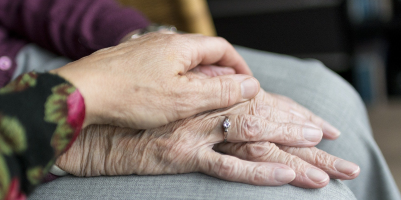 Die Hand einer jungen Frau hält die Hand einer alten Frau.