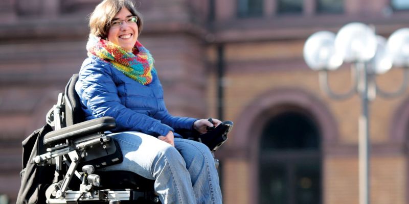 Eine junge Frau sitzt im Elektro-Rollstuhl.