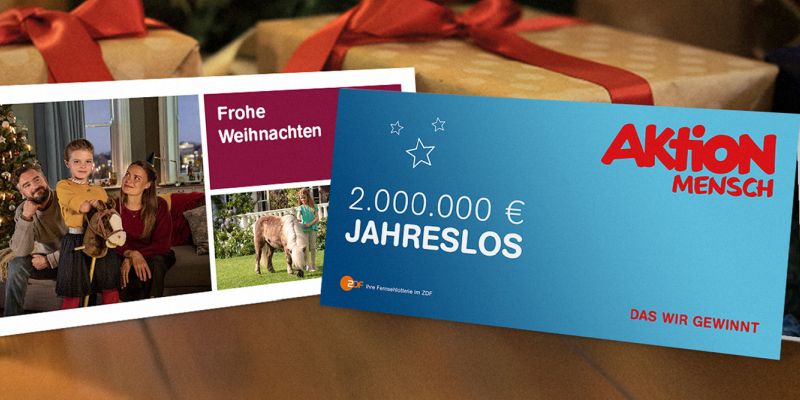 Ein Jahreslos lehnt an einem verpackten Geschenk.