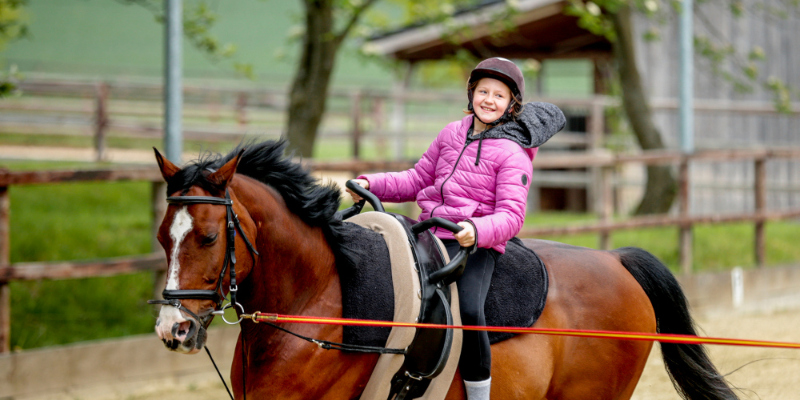Ein Mädchen reitet auf einem Pferd.