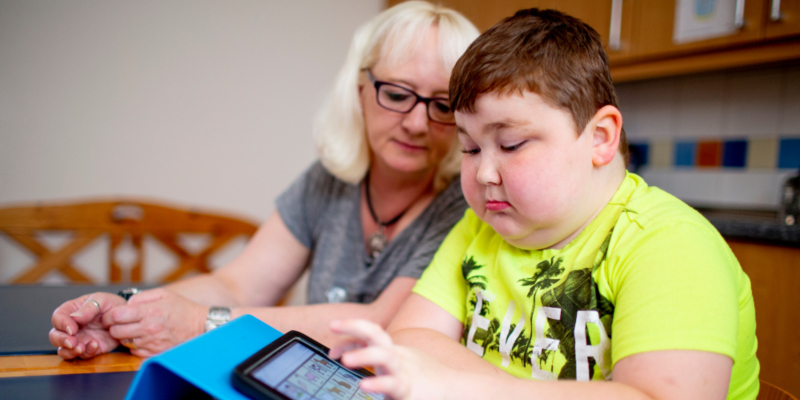 Eine Frau und ein Junge lernen gemeinsam an einem Tablet.
