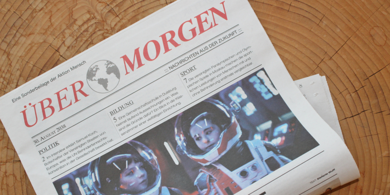 Die ZEIT-Beilage der Aktion Mensch liegt auf einem hellen Holztisch.