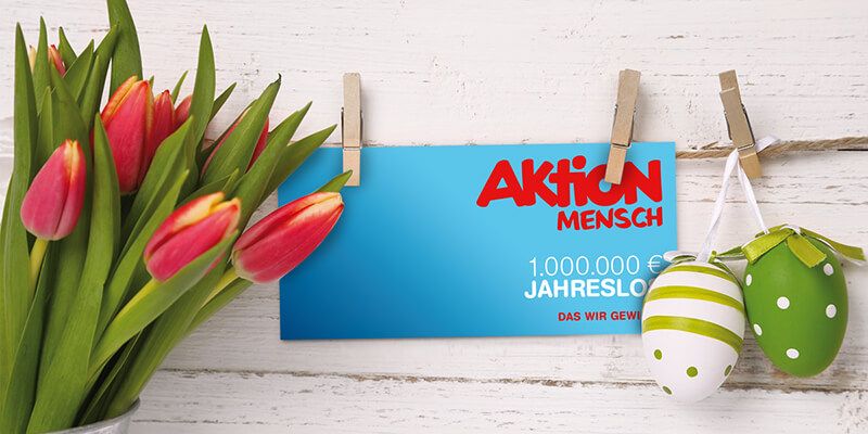 Ein Tulpenstauß, zwei bemalte Ostereier und ein Jahreslos der Aktion Mensch hängen an einer Wäscheleine