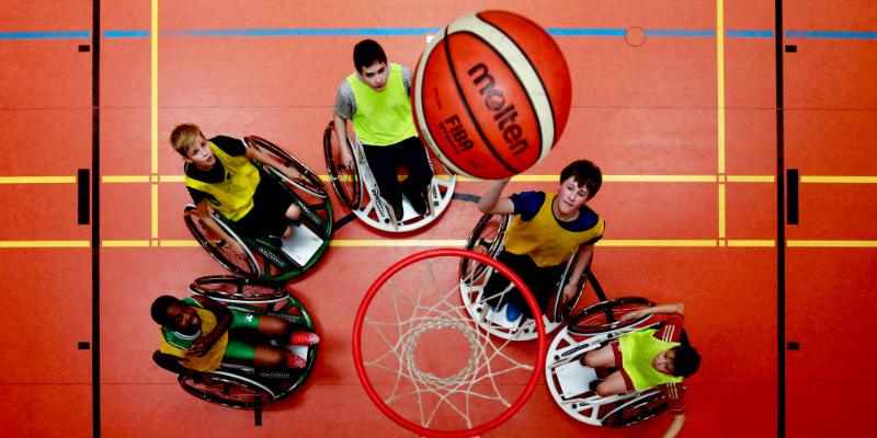 Fünf Jugendliche spielen Rollstuhlbasketball.