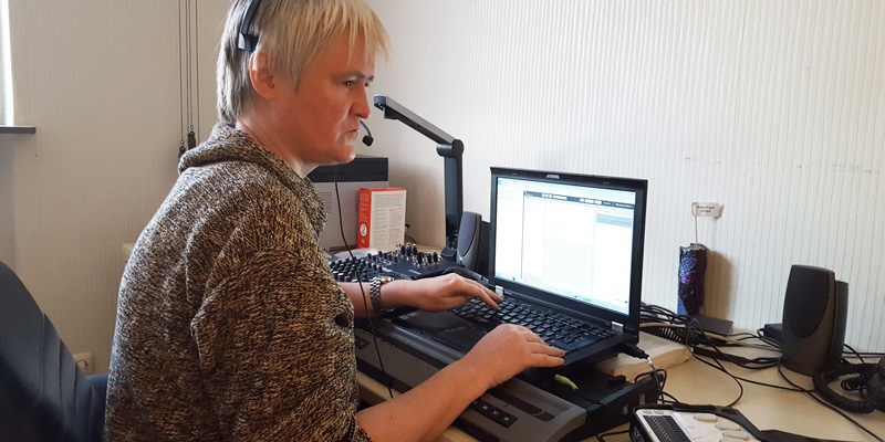 Eine Frau mit Headset tippt auf einem Laptop.