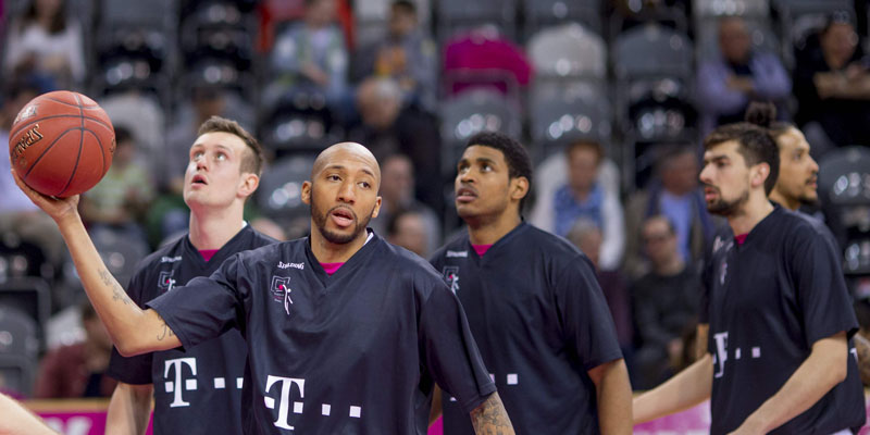 Männer in Sporttrikots mit einem Basketball