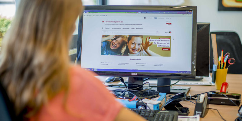 Eine Frau sitzt an einem PC, auf dem die Seite des Familienratgebers geöffnet ist.