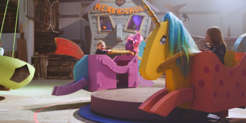 Kinder mit und ohne Behinderung auf einem kunterbunten Spielplatz.