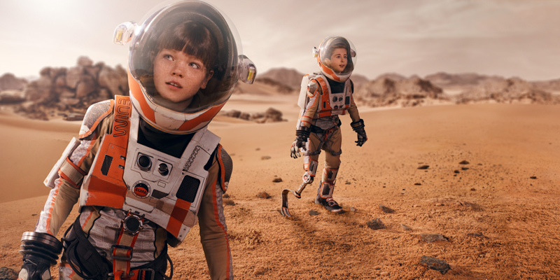 Zwei Kinder mit und ohne Behinderung auf einer Marslandschaft