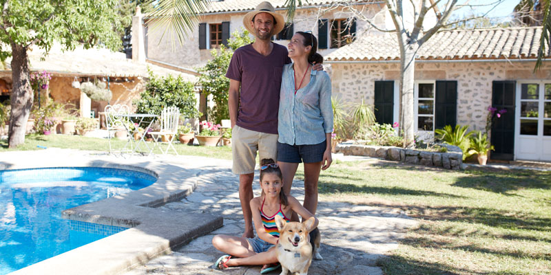 Ein Mann, eine Frau, ein Kind und ein Hund vor einer spanischen Finca
