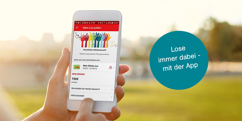 Eine Hand hält ein Smartphone mit der Aktion Mensch-App. Auf einem Störer steht: Alle Lose in unserer App
