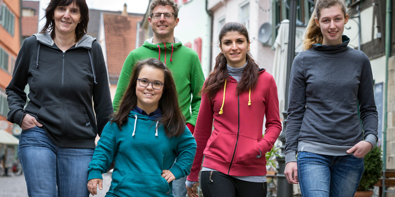 Fünf Menschen mit verschiedenen Sweatshirts gehen in Richtung der Kamera.