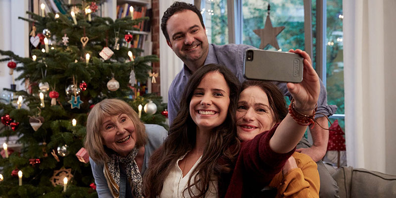 Eine Familie macht ein Selfie vor dem Weihnachtsbaum.