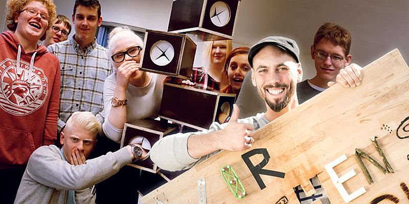 Eine Gruppe Jugendlicher mit Sehbehinderung steht um einen Tastboxen-Baum.