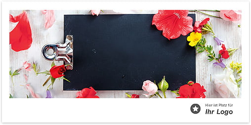 Schwarzes Klemmbrett auf grauem Holztisch eingebettet in eine rote Blumendekoration