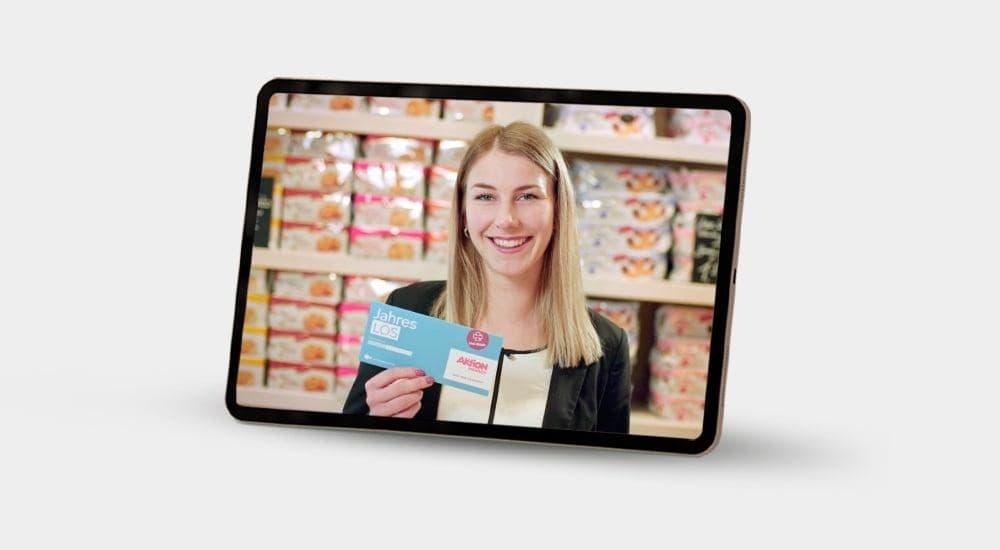 Auf einem Tablet ist eine Frau von Coppenrath Feingebäck, die ein Aktion Mensch Los zeigt.