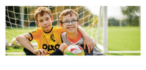 2 Jungen sitzend mit Ball vor einem Tor